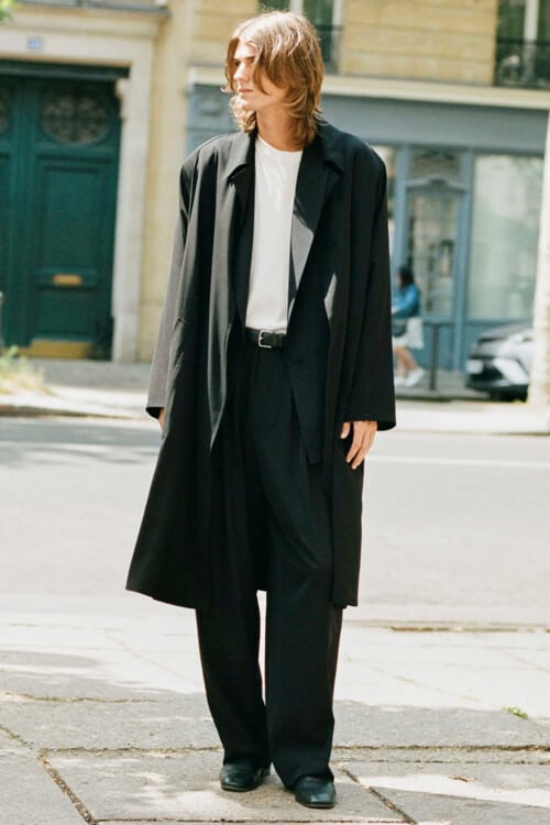Men's loose black suit, white tucked in T-shirt and long black trench coat outfit
