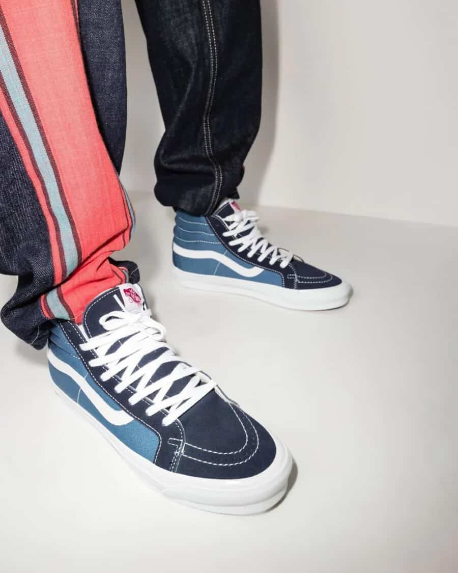 Vans Sk8-Hi blue and black canvas sneakers worn on feet with raw denim