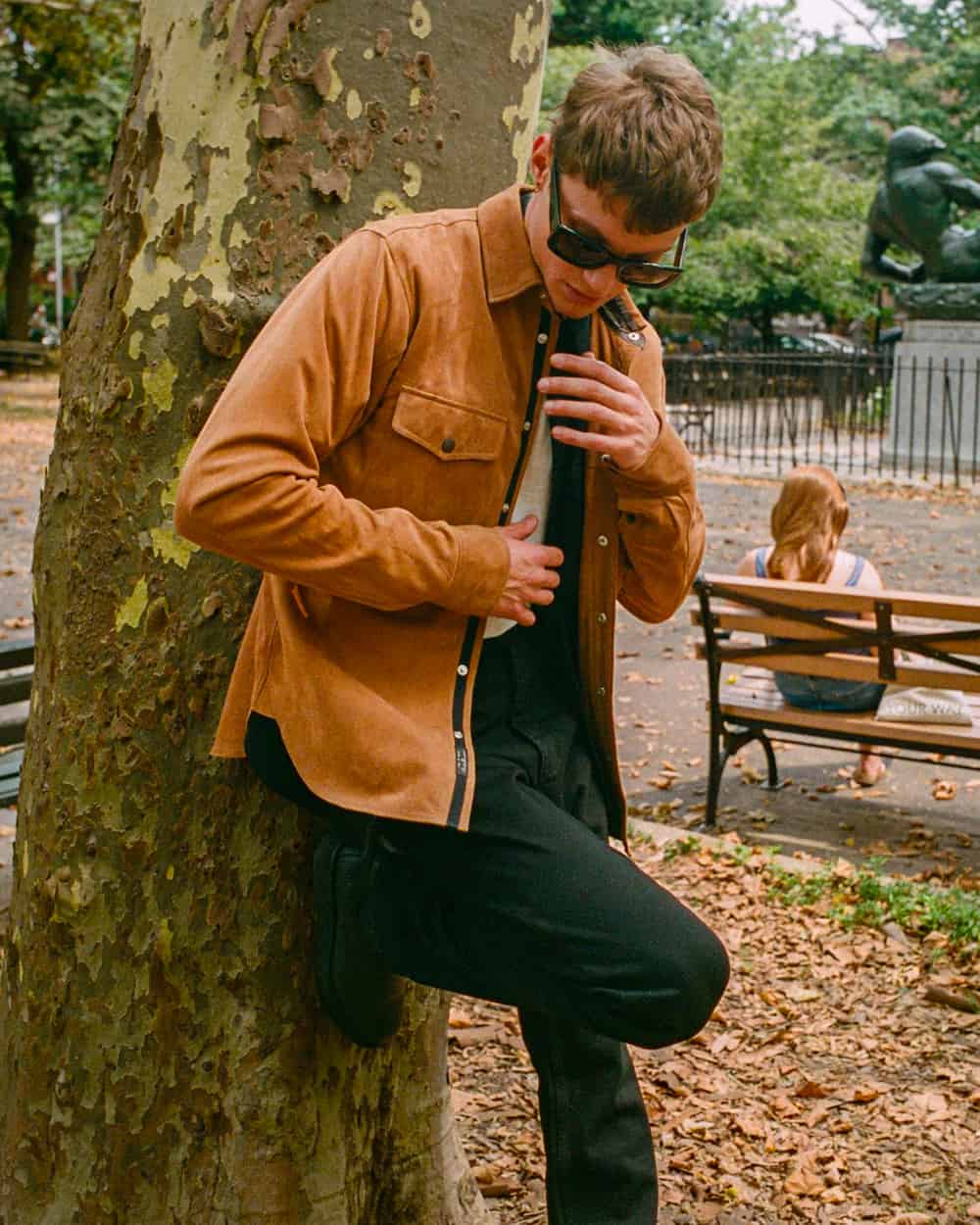 Man wearing a brown suede shacket over a white T-shirt with black pants and sunglasses