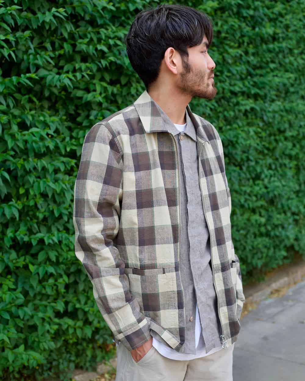 Man wearing a folk check shacket over a grey shirt with stone chinos