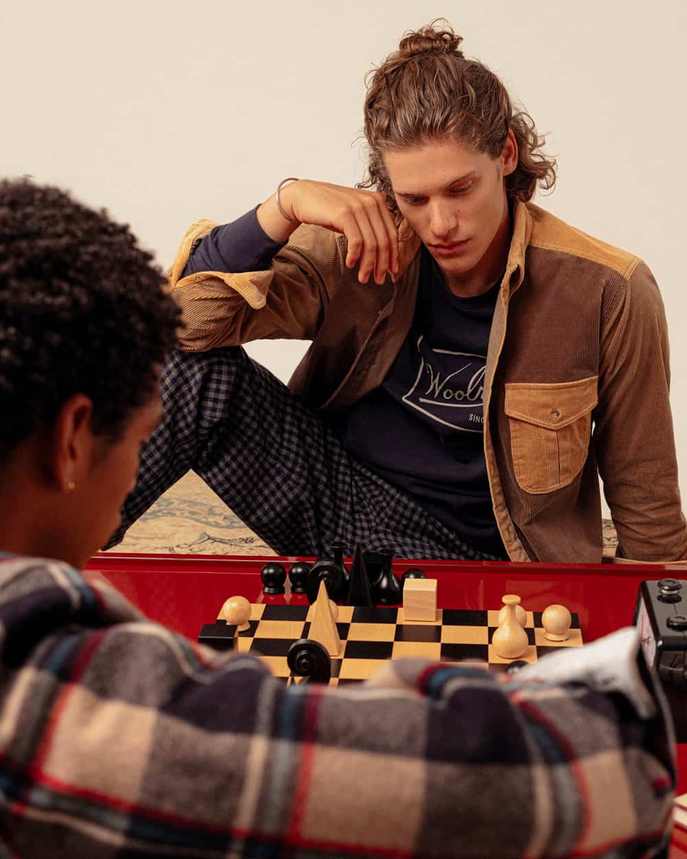 Two men playing chess wearing heavyweight Woolrich shackets in check and brown cord