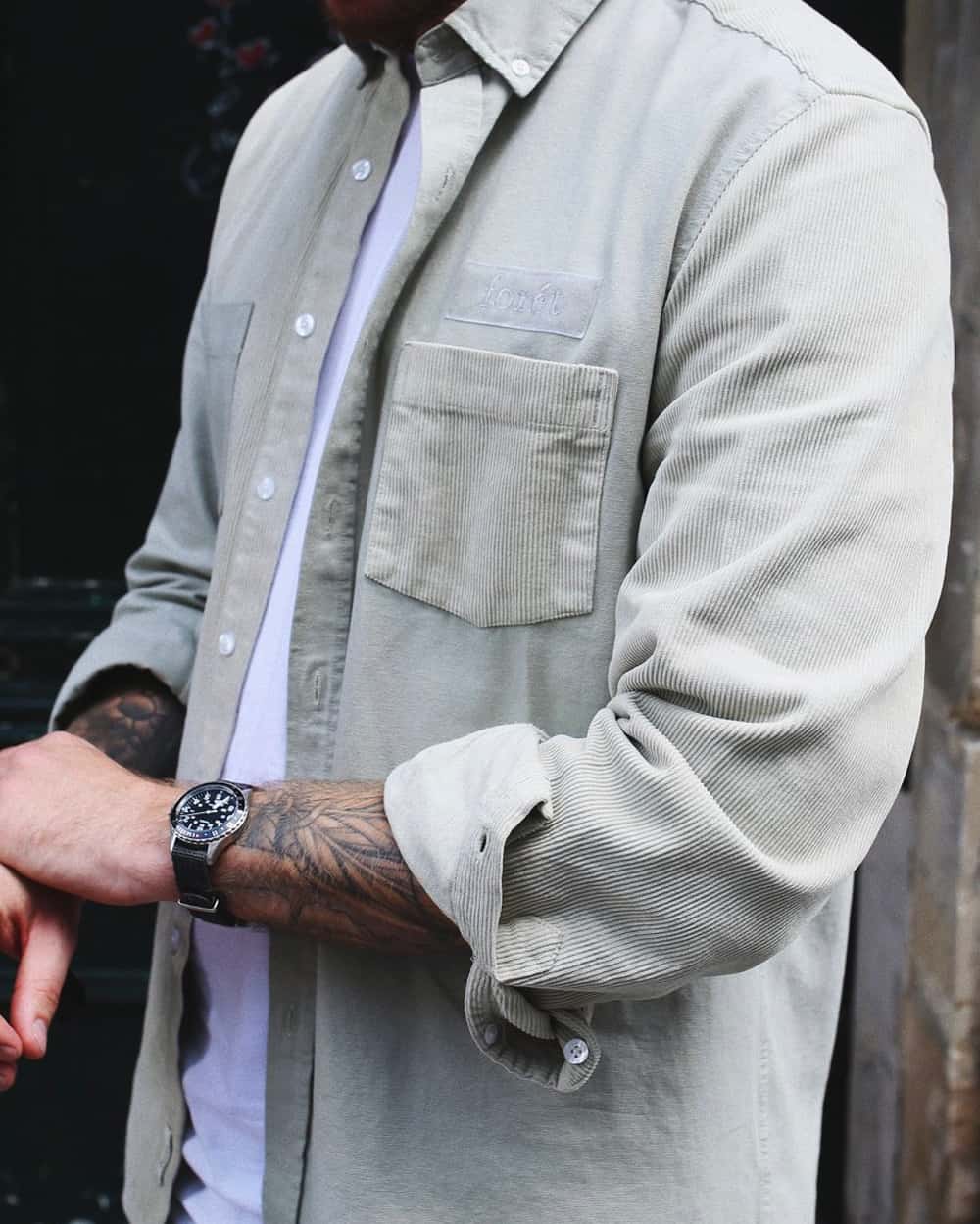 Close up of a man wearing light grey corduroy shacket over a white T-shirt