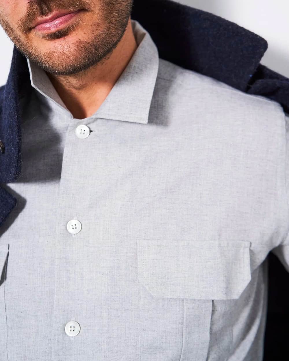 Close up of a grey patch pocket flannel overshirt buttoned up to the top