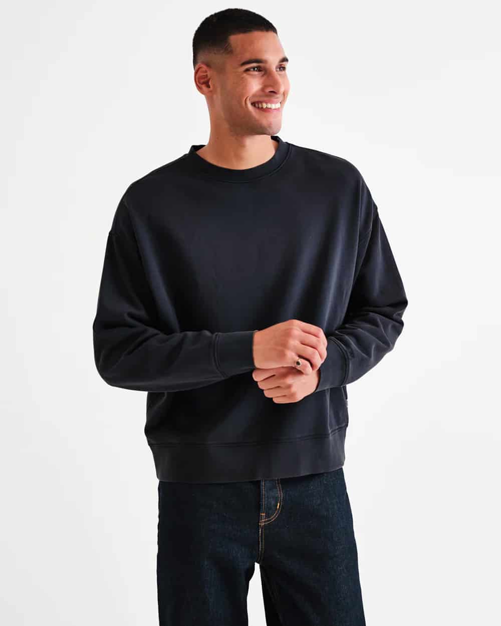 Man wearing Wax London black oversized sweatshirt with dark raw denim jeans