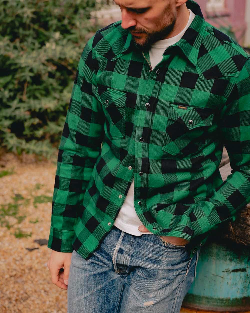 Man wearing a heavy green/black check flannel shirt by Iron Heart with faded jeans and a white T-shirt