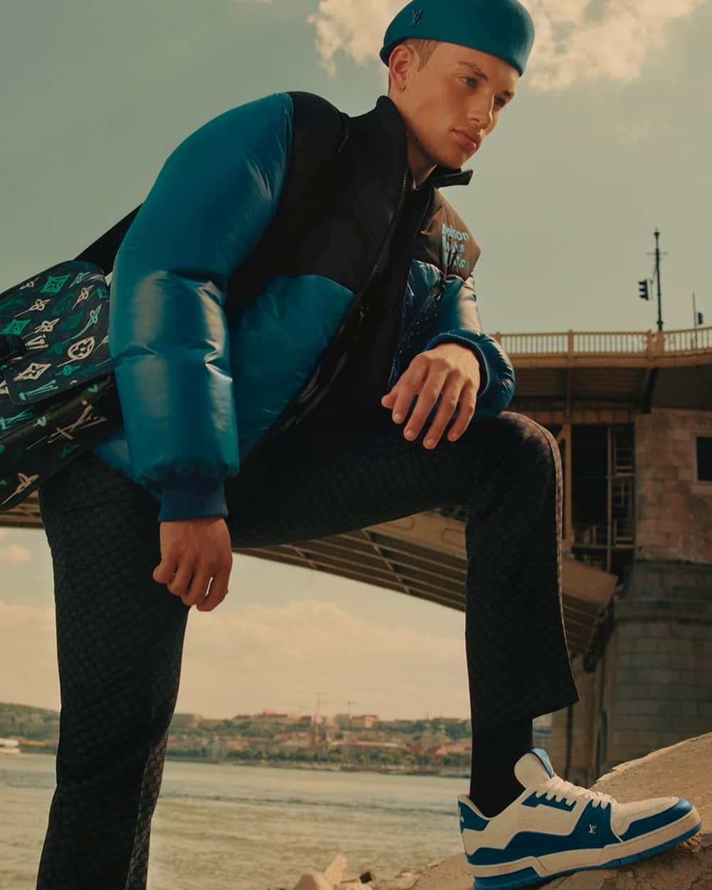 Man wearing Louis Vuitton blue and white chunky sneakers on feet with navy pants and blue puffer jacket