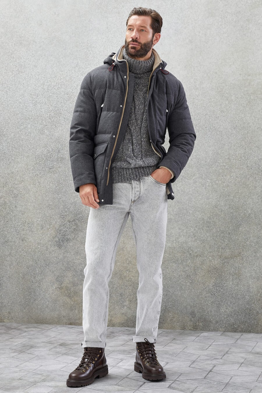 Men's light grey jeans, chunky grey cable knit turtleneck, dark grey puffer jacket and brown leather hiking boots outfit