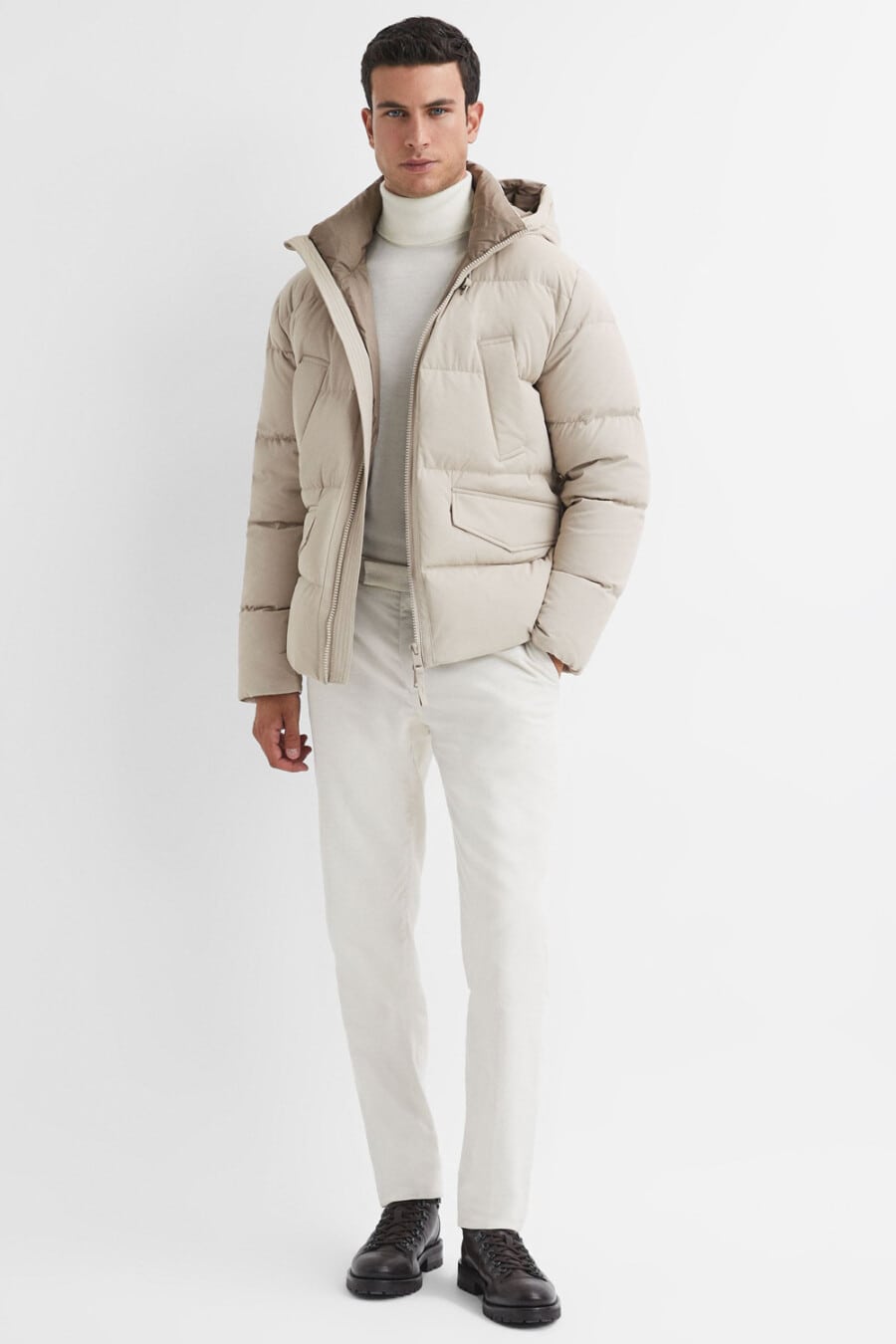 Men's white tailored pants, white turtleneck, off white puffer jacket and brown leather boots outfit