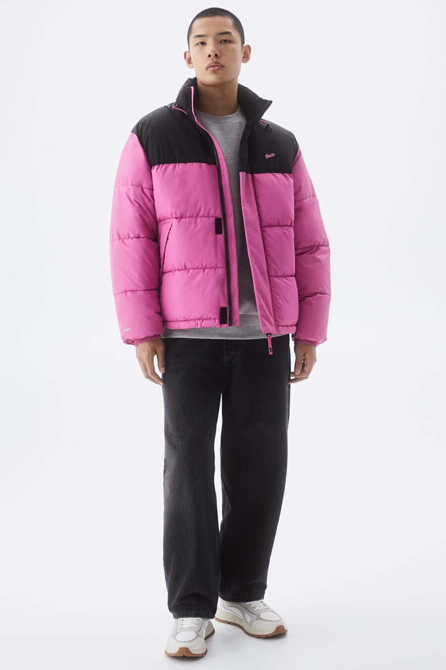 Men's black baggy jeans, grey T-shirt, bright pink puffer jacket and chunky white sneakers outfit