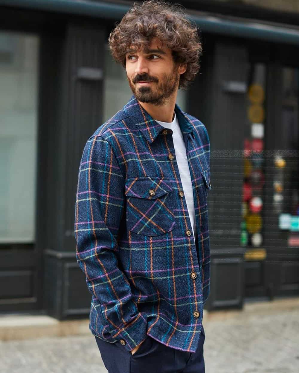 Man wearing a blue check flannel shirt by Portuguese Flannel over a white T-shirt with navy pants 