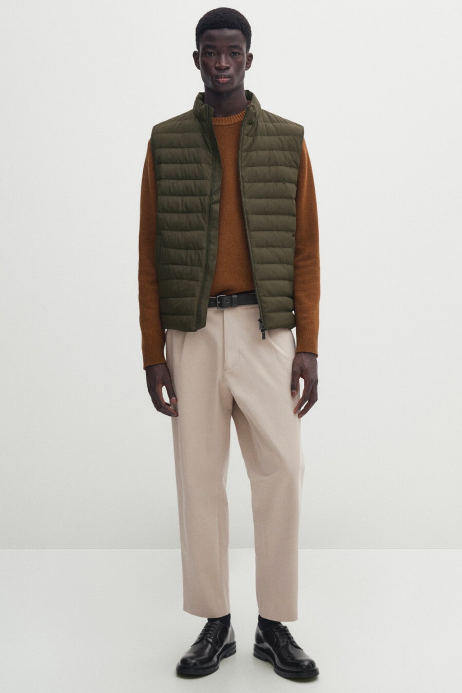 Men's wide-leg cream pants, brown long-sleeve top, green puffer vest and black leather Derby shoes outfit