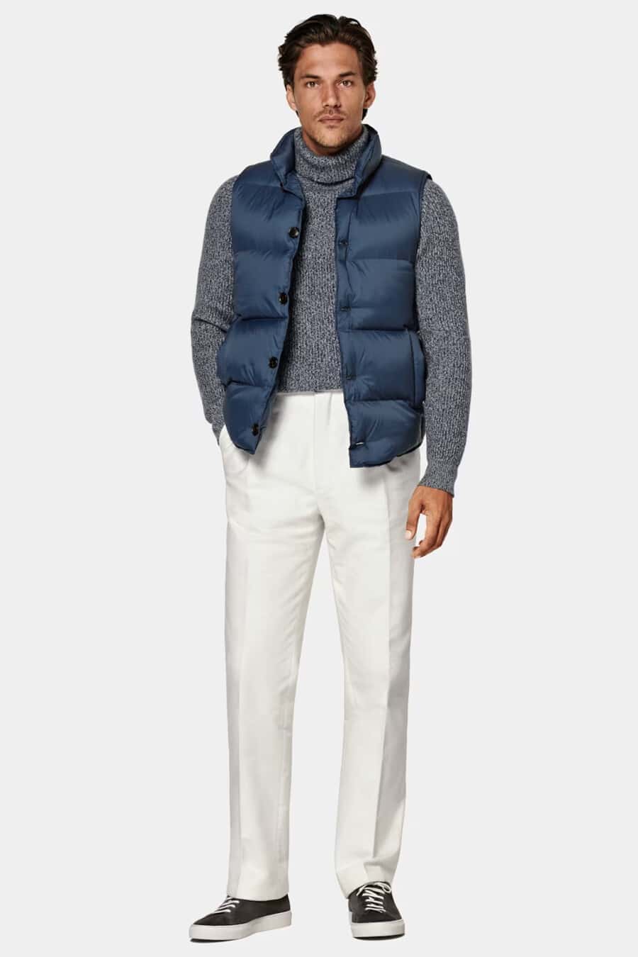 Men's white pants, grey turtleneck, blue puffer vest and brown suede sneakers outfit