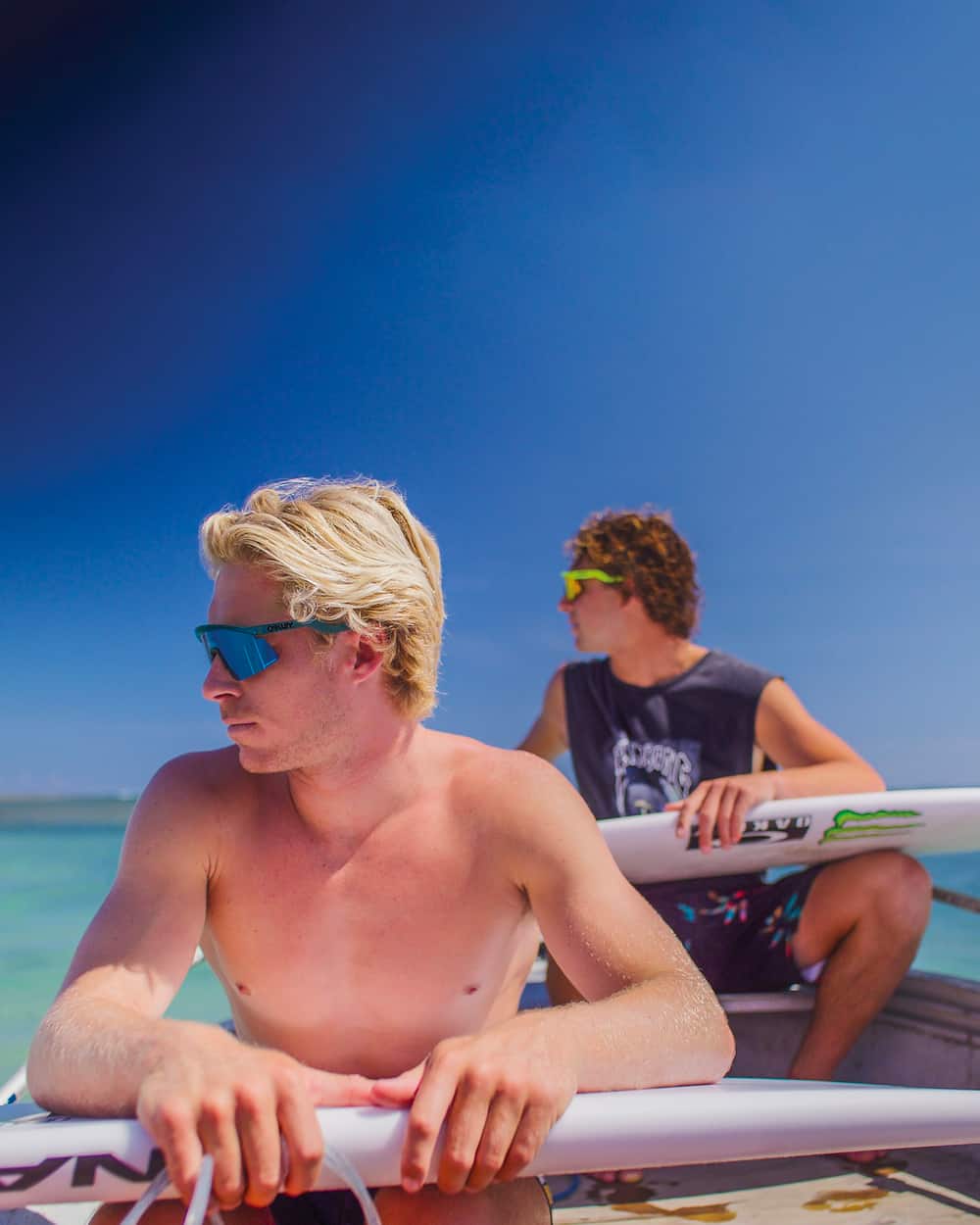 Two men wearing Oakley sunglasses on surfboards