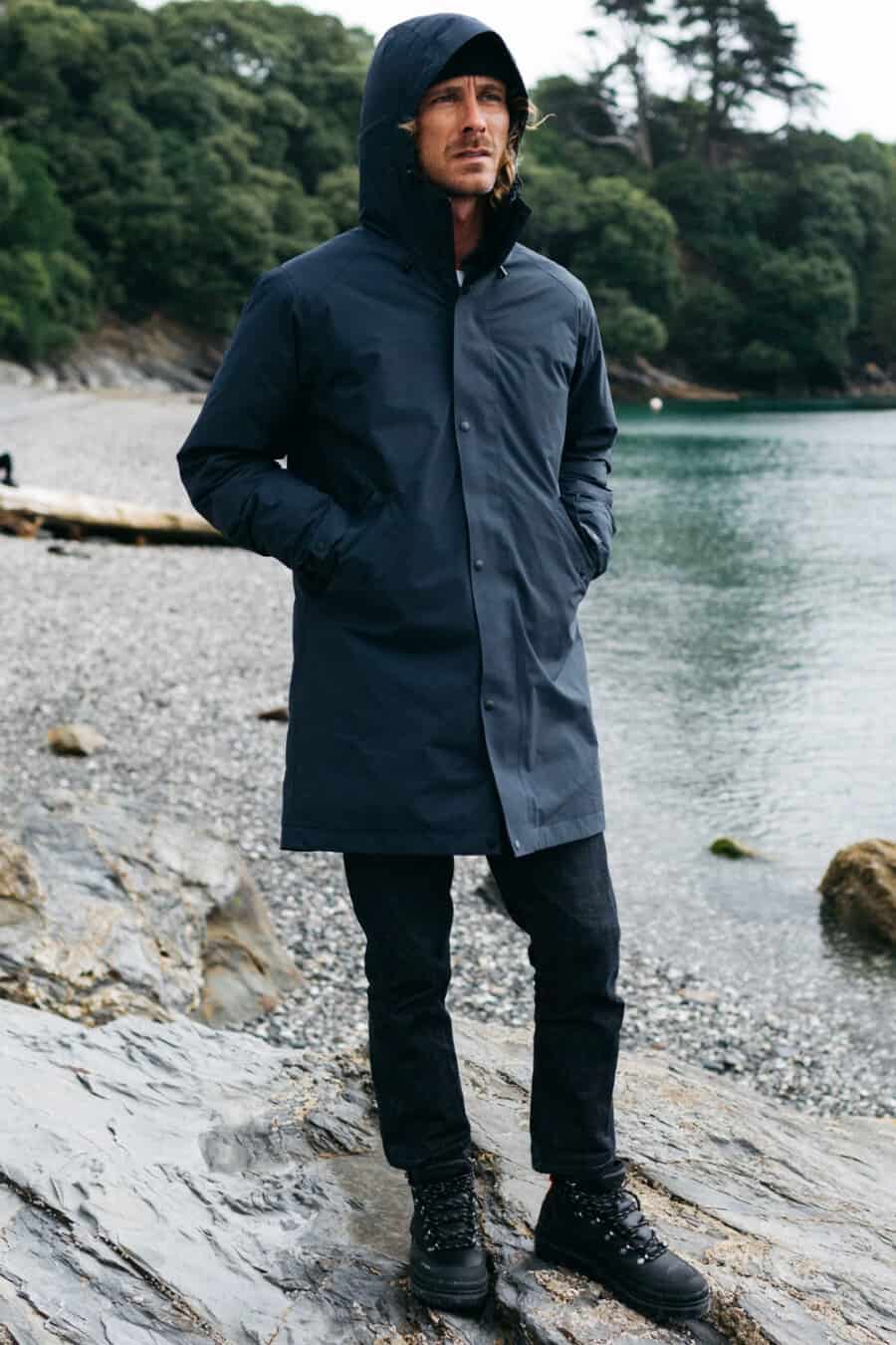 Man wearing navy waterproof gore-tex jacket with navy pants and black hiking boots