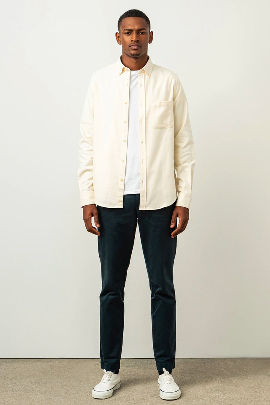 Men's navy pants, white T-shirt, off-white shacket and white canvas sneakers outfit