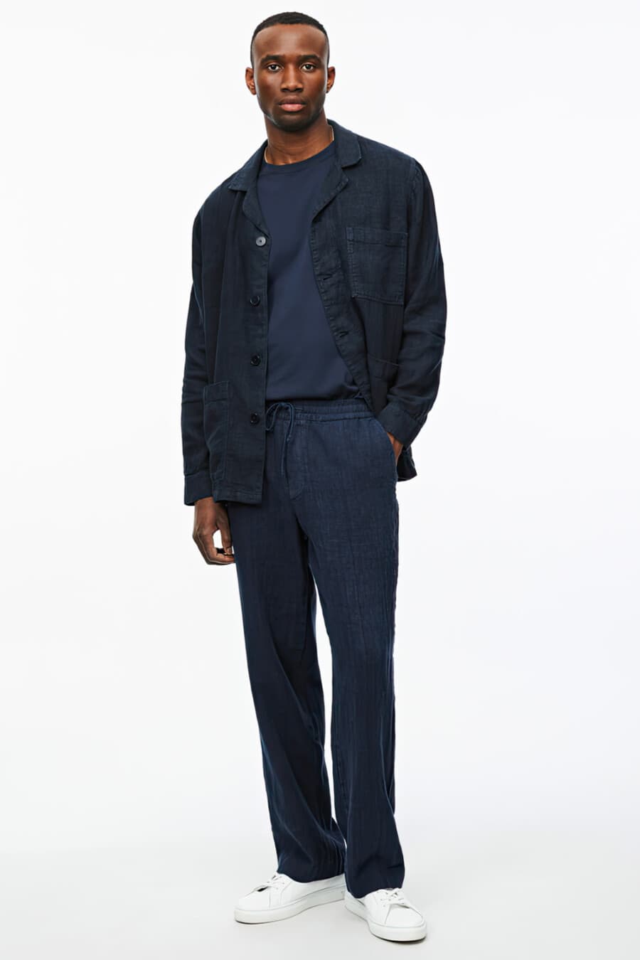 Men's navy linen overshirt, drawstring navy pants, tucked in blue T-shirt and white sneakers outfit