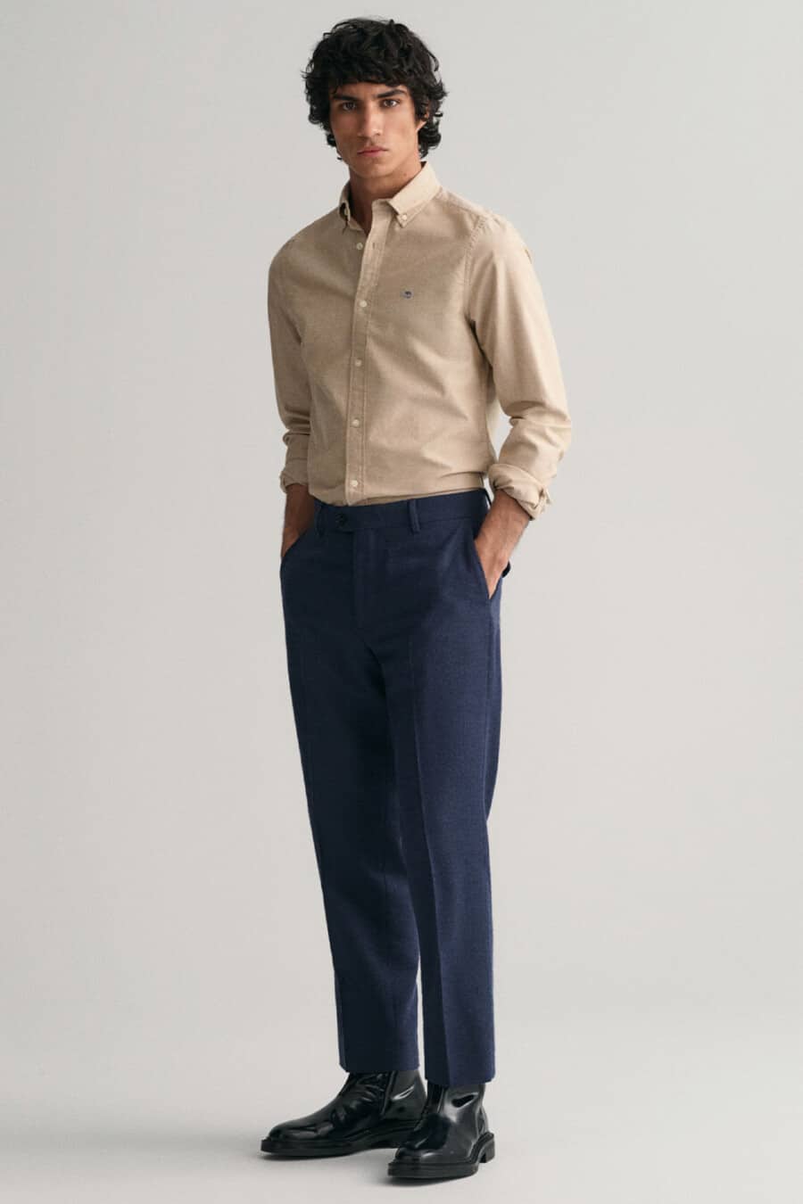 Men's navy tailored pants, tucked in light brown Oxford shirt and black leather Chelsea boots outfit