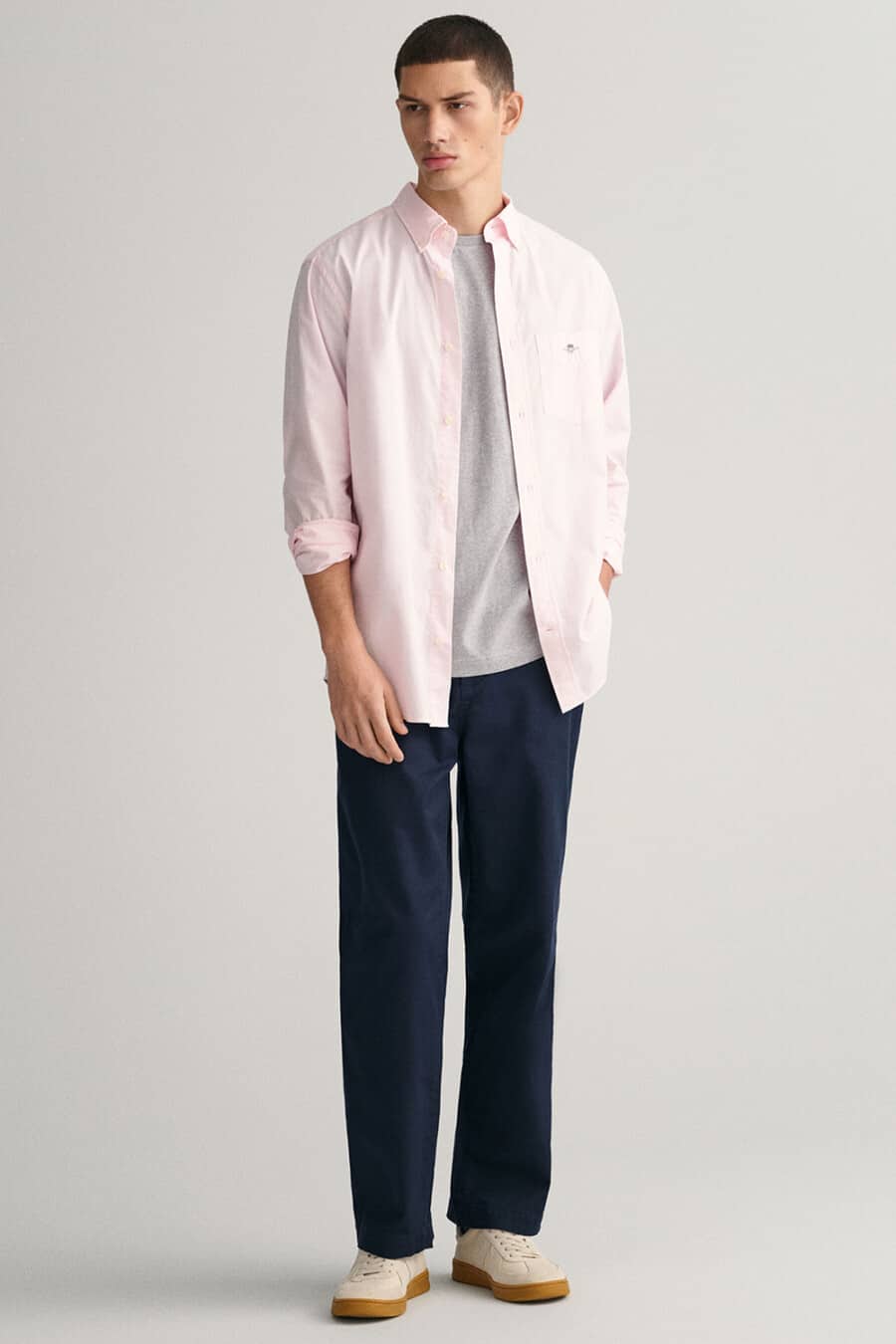 Men's navy chinos, grey T-shirt, open pink Oxford shirt and beige gum sole sneakers outfit