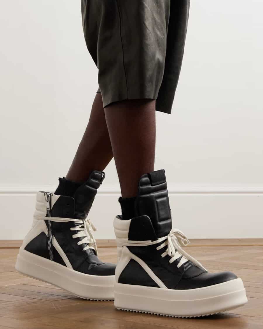 Man wearing Rick Owens Geobasket Mega Bumper Exaggerated-Sole Two-Tone Leather High-Top Sneakers on feet with black loose leather shorts