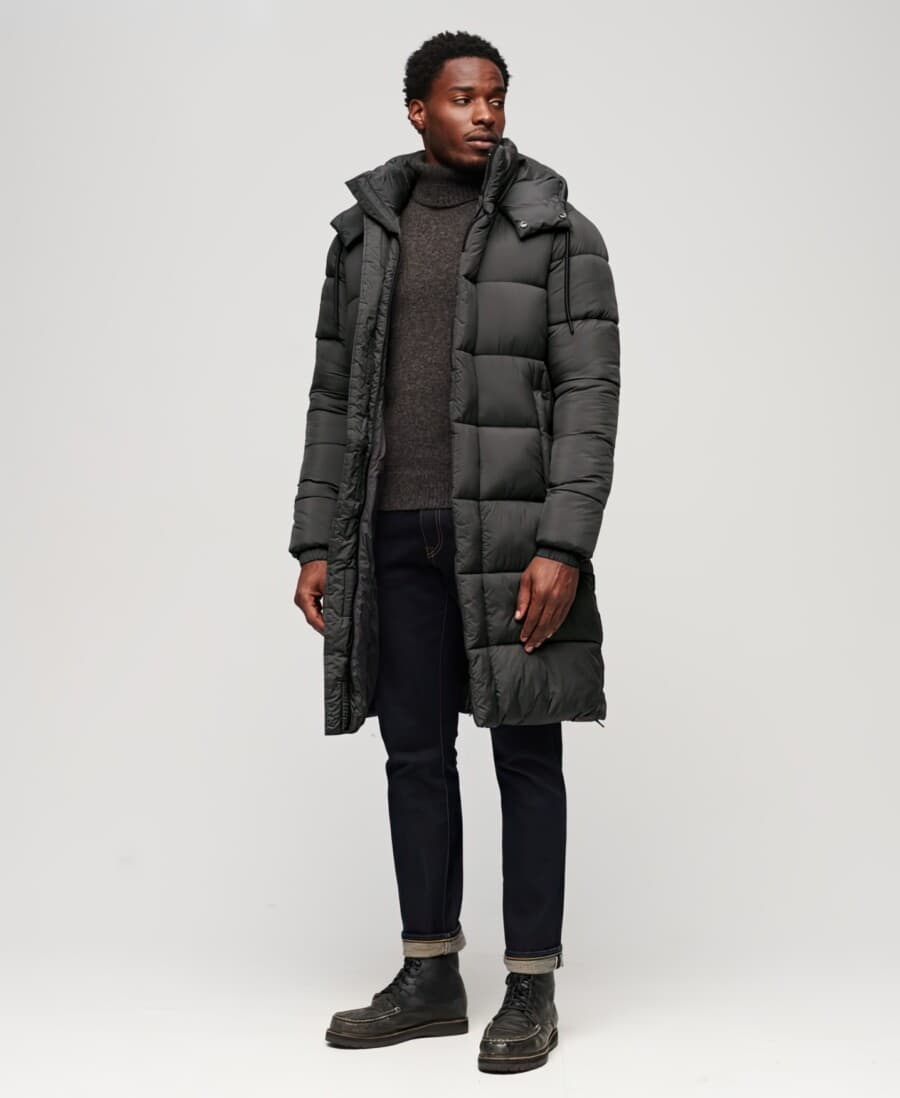 Men's raw denim jeans, charcoal turtleneck, long length grey puffer jacket and black leather boots outfit