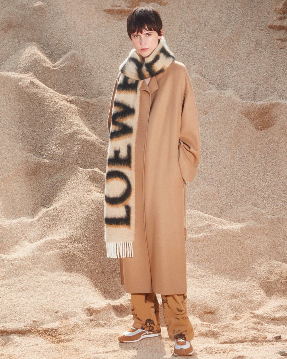 Model wearing an oversized camel overcoat with an oversized branded Loewe scarf