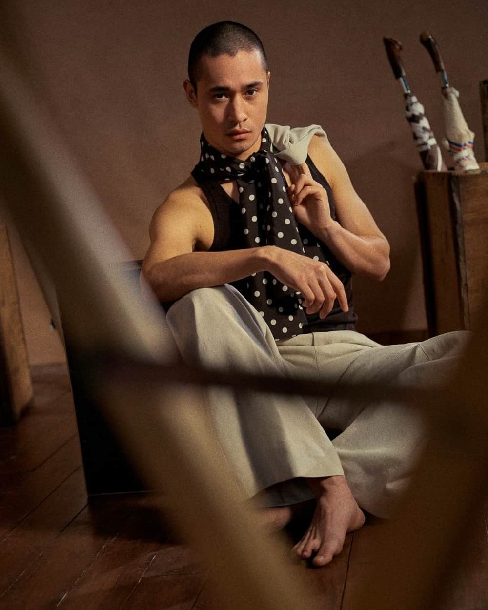 Man wearing black tank top, grey pants and a Connolly black/white polka dot silk scarf