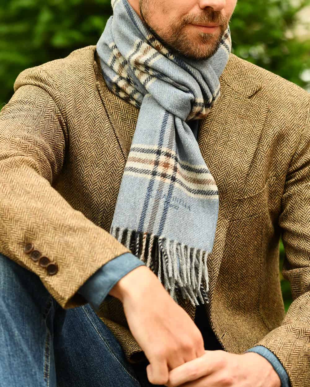 Man in tweed blazer and jeans wearing a E. Marinella light blue checked scarf