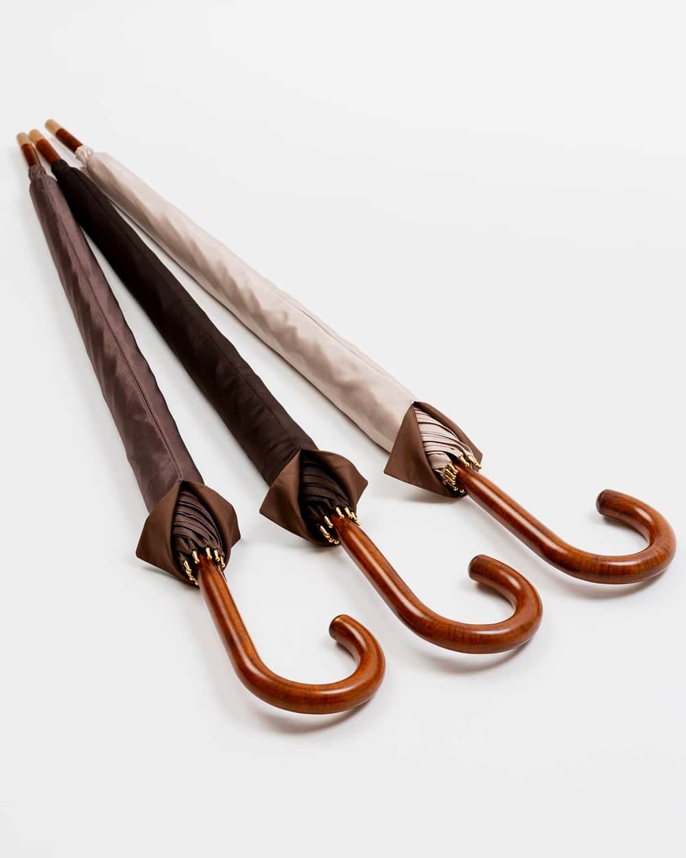 Three premium wooden handle umbrellas by Michel Heurtault with brown and beige fabric canopies