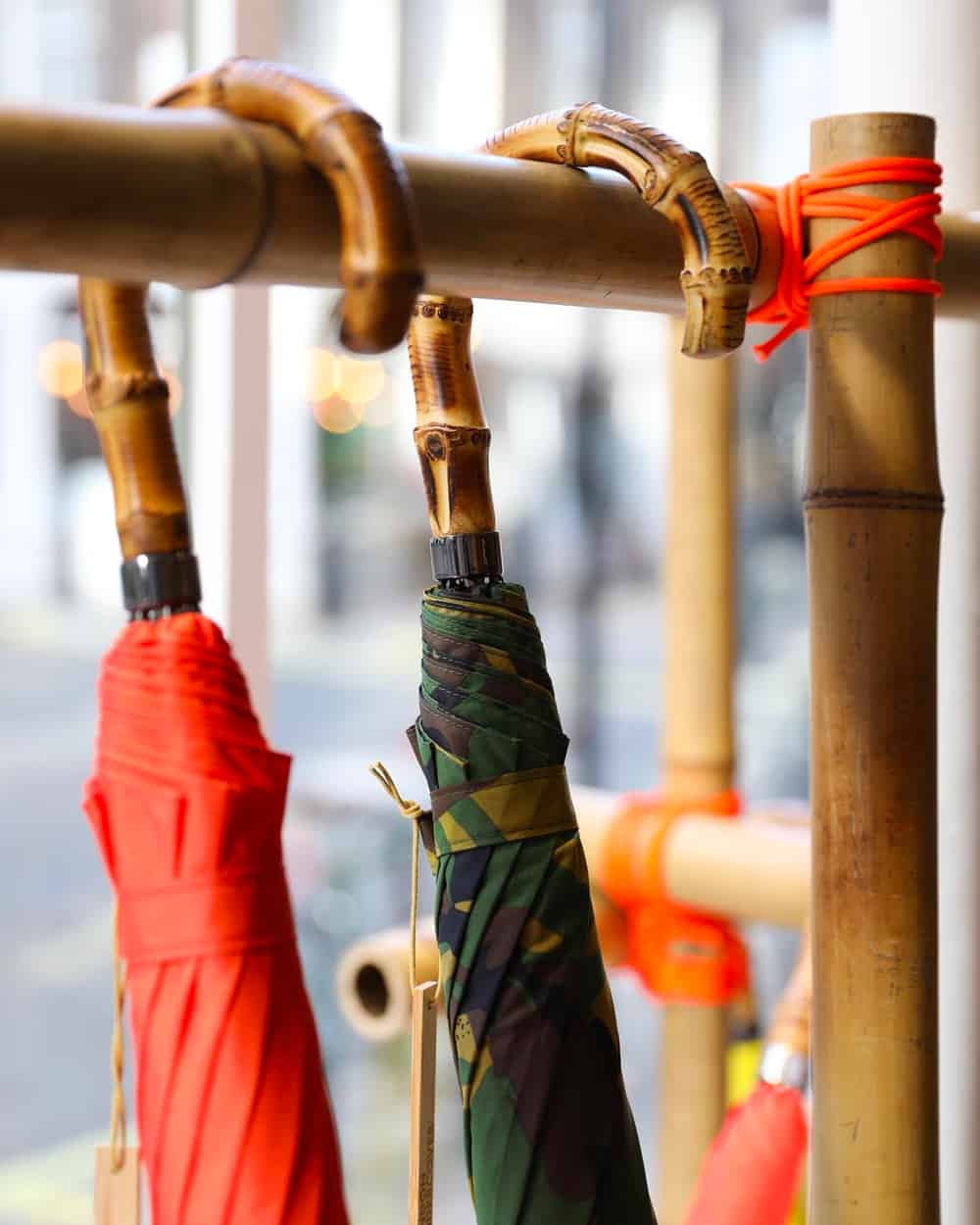 Two premium London Undercover umbrellas with wooden cane handles and bright red and green camo print canopies