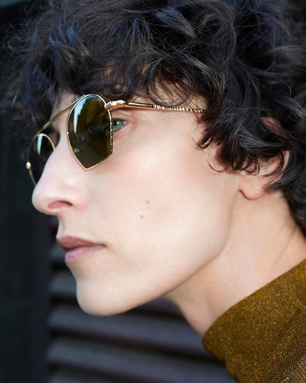 Man wearing Ahlem men's gold frame sunglasses with green gradient lenses