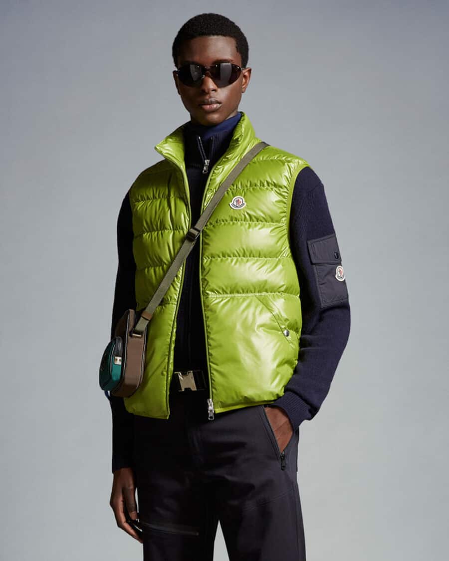 Men's navy technical pants, navy quarter-zip sweater, lime green puffer vest and crossbody bag by Moncler