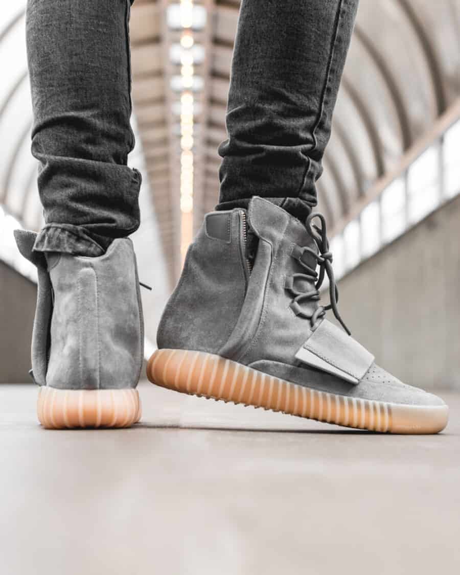 Yeezy Boost 750 sneakers worn on feet with stacked black denaim jeans