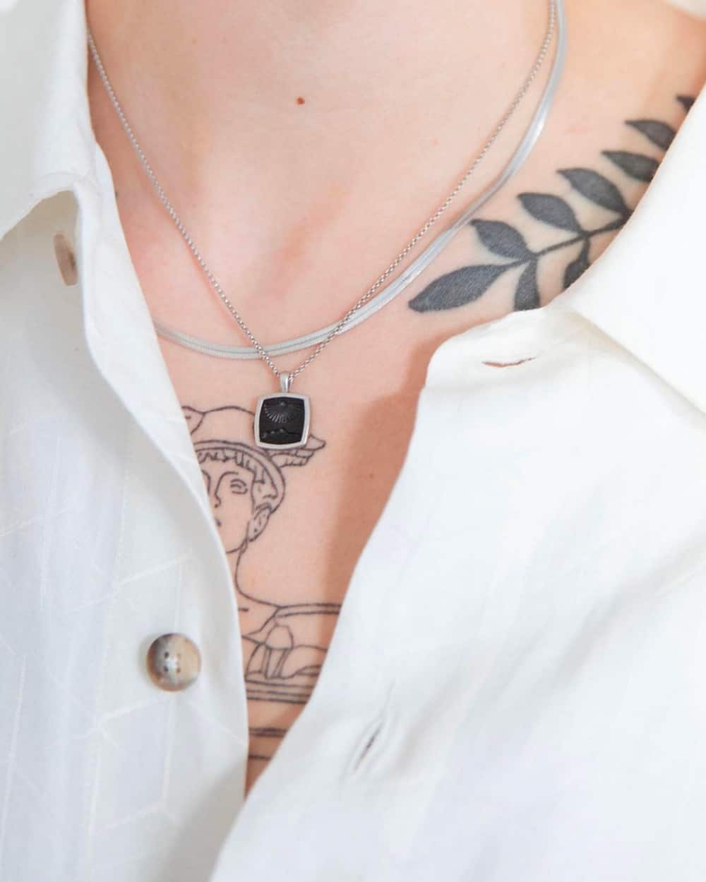 Man wearing two Tom Wood silver necklaces, one with a black pendant