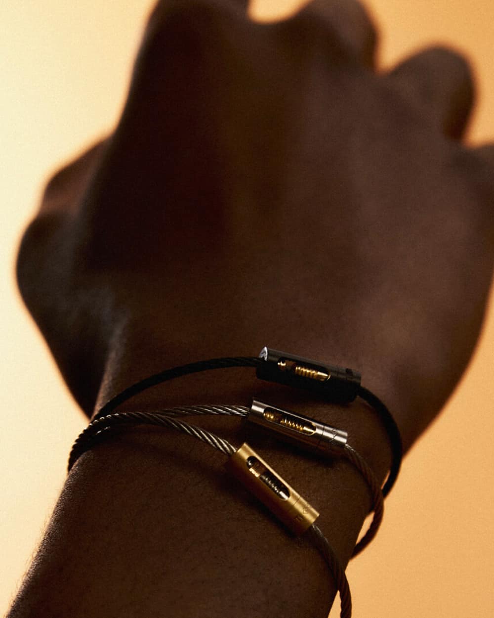 Black man wearing three Le Gramme bracelets in silver, black and gold