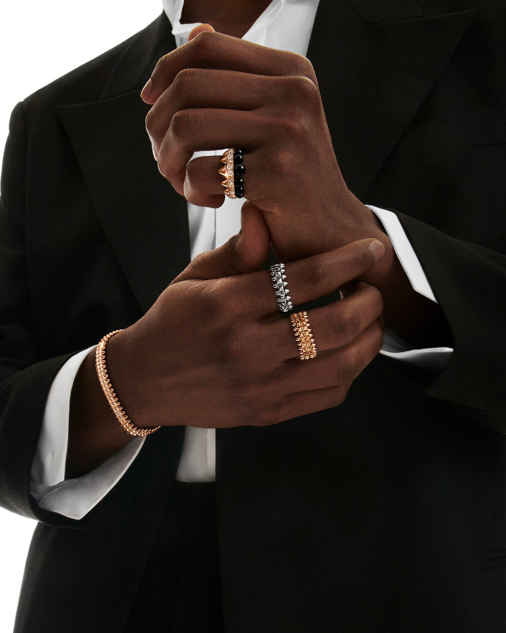 Black man wearing multiple luxury Cartier rings in silver and gold, and a gold bracelet
