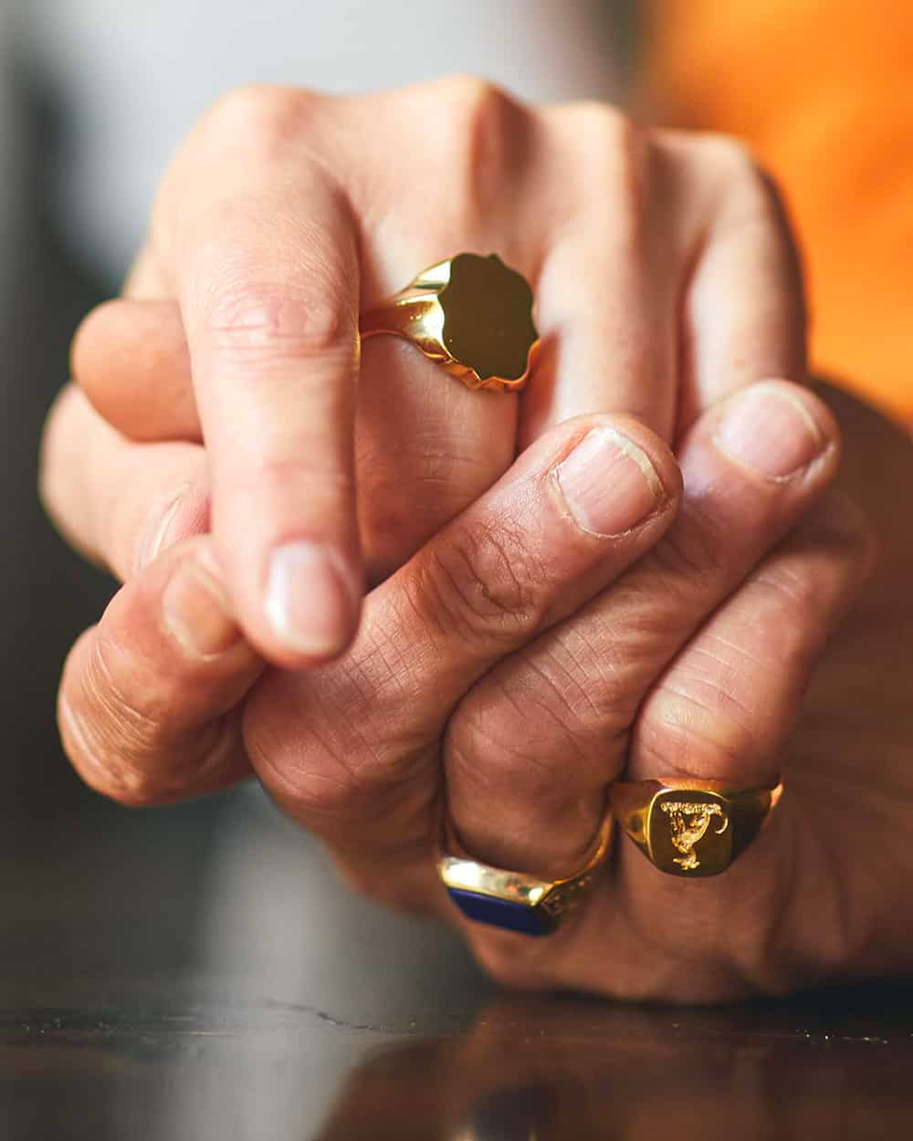 Close up of a man wearing three Rebus luxury gold signet rings