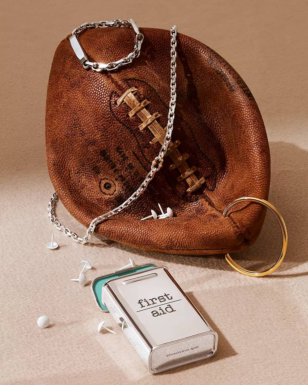 Men's Tiffany & Co. silver and gold jewellery on an American football