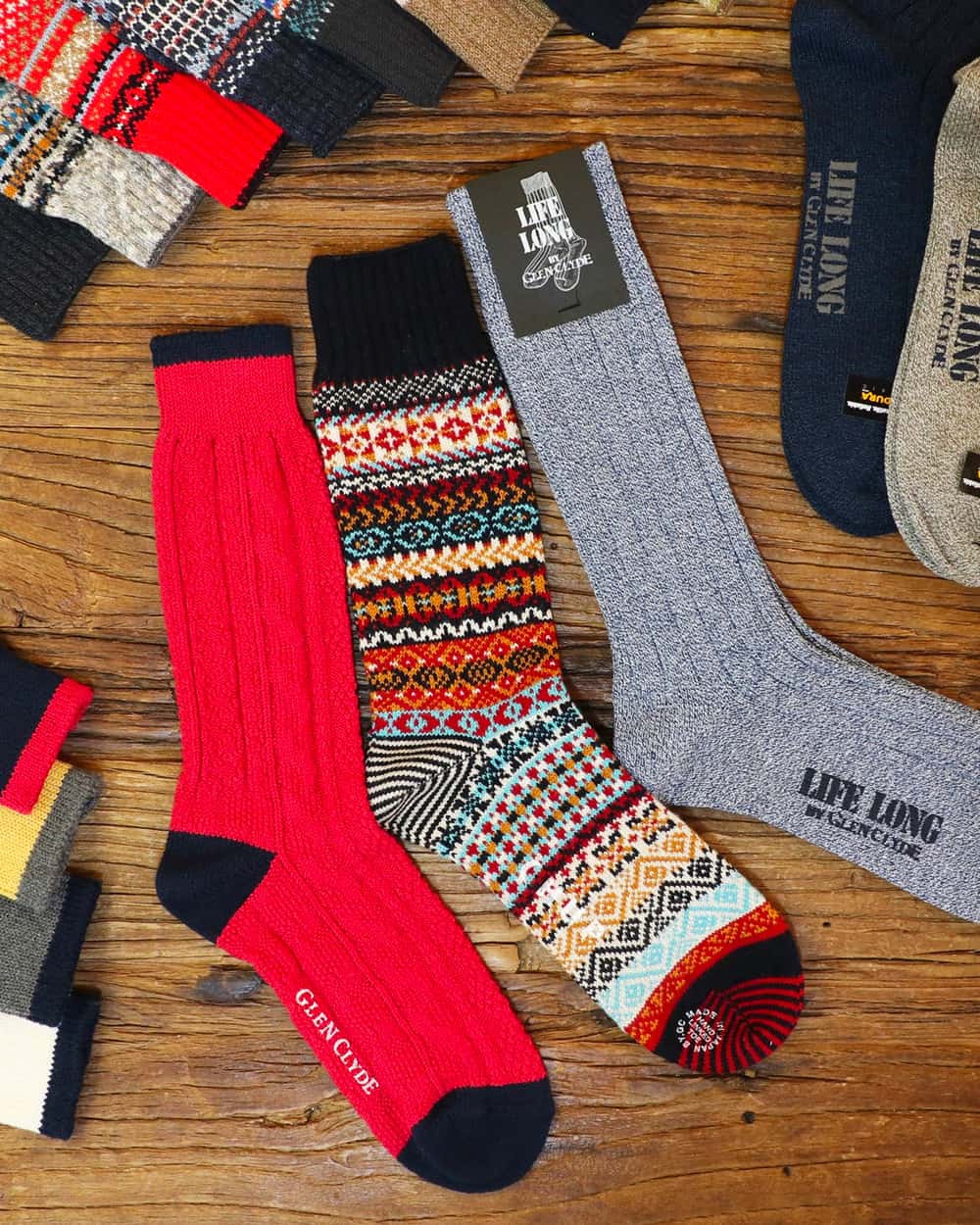 A selection of men's Chup socks in plain ribbed and patterned styles laid on wood
