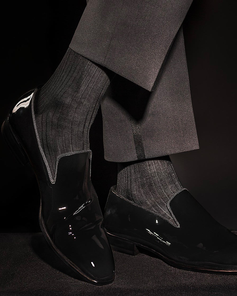 Man wearing William Abraham luxury charcoal dress socks with black patent slippers and tuxedo pants