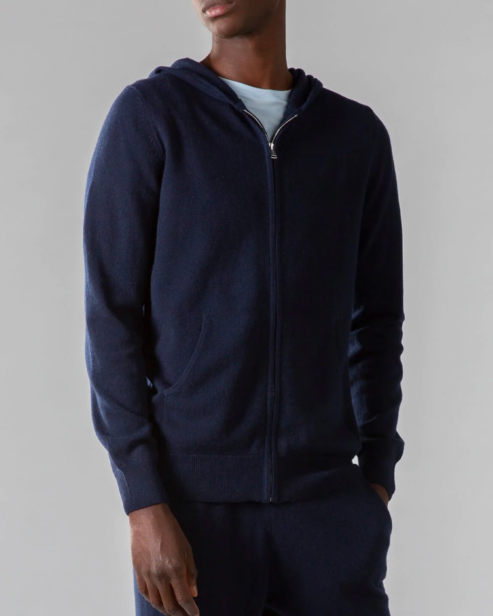 Black man wearing a matching cashmere navy hoodie and sweatpants with a white T-shirt
