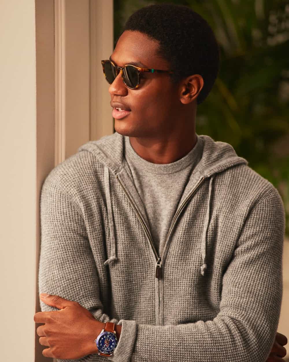 Black man wearing a luxury waffle knit Ralph Lauren hoodie over a grey T-shirt with tortoiseshell round lens sunglasses