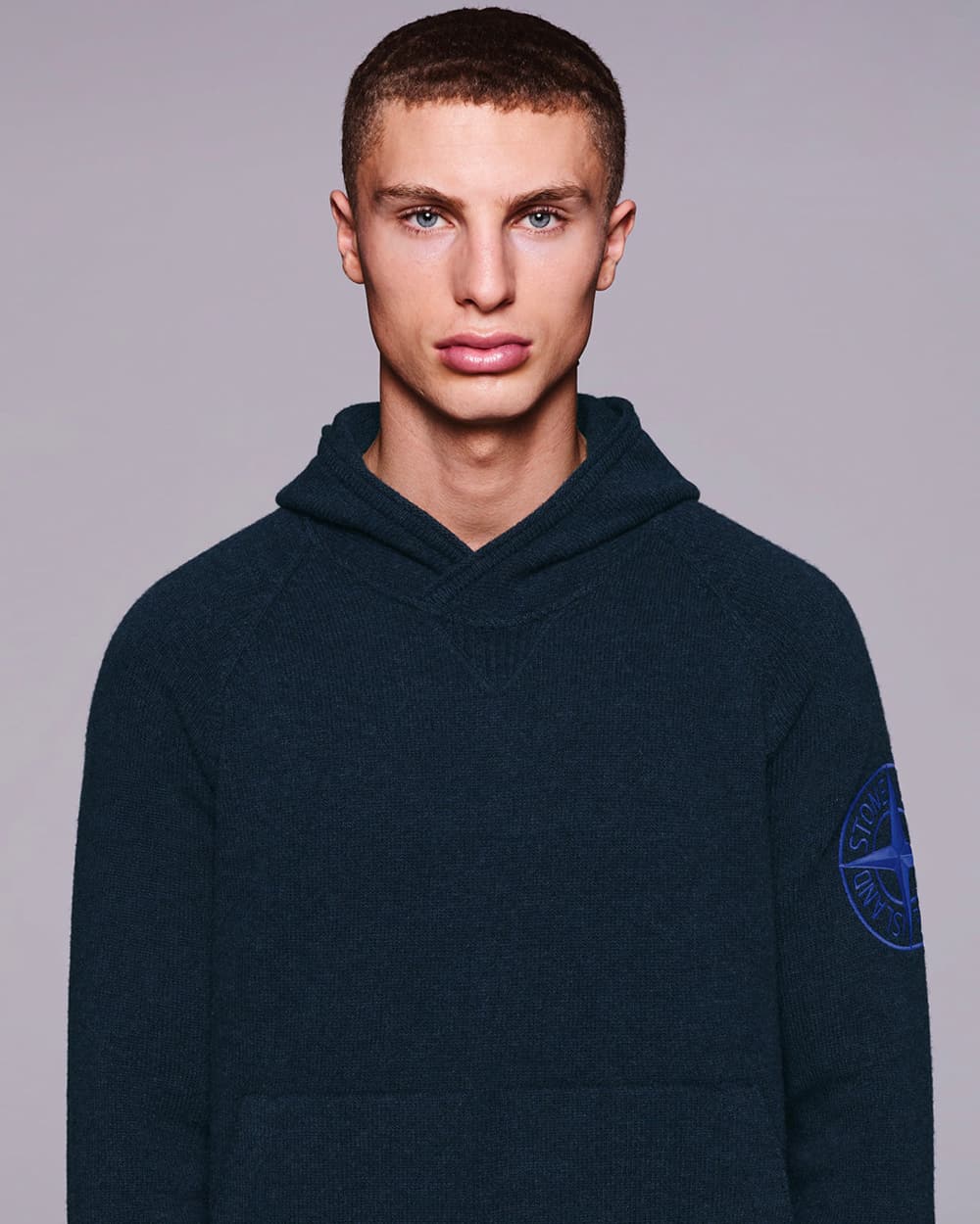 Man wearing a navy Stone Island hoodie with embroidered badge on the sleeve