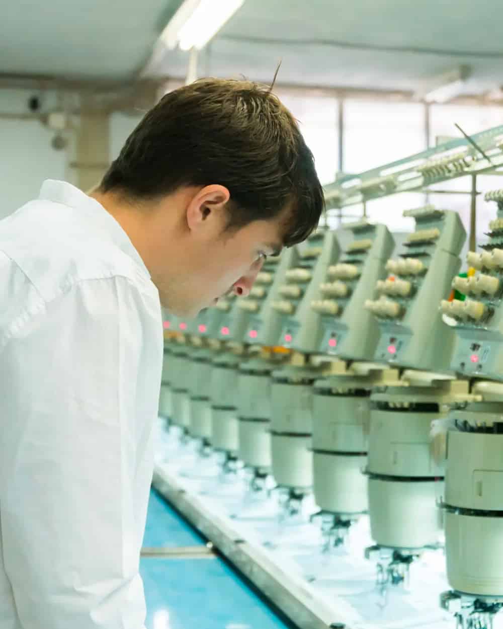 Man producing a premium hoodie using a cotton manufacturing machine