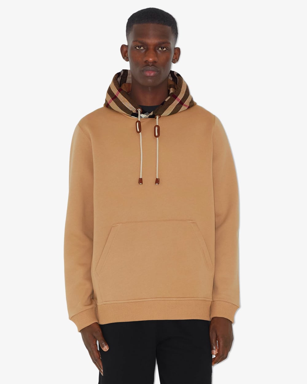 Black man wearing a camel Burberry hoodie with checked hood and black pants