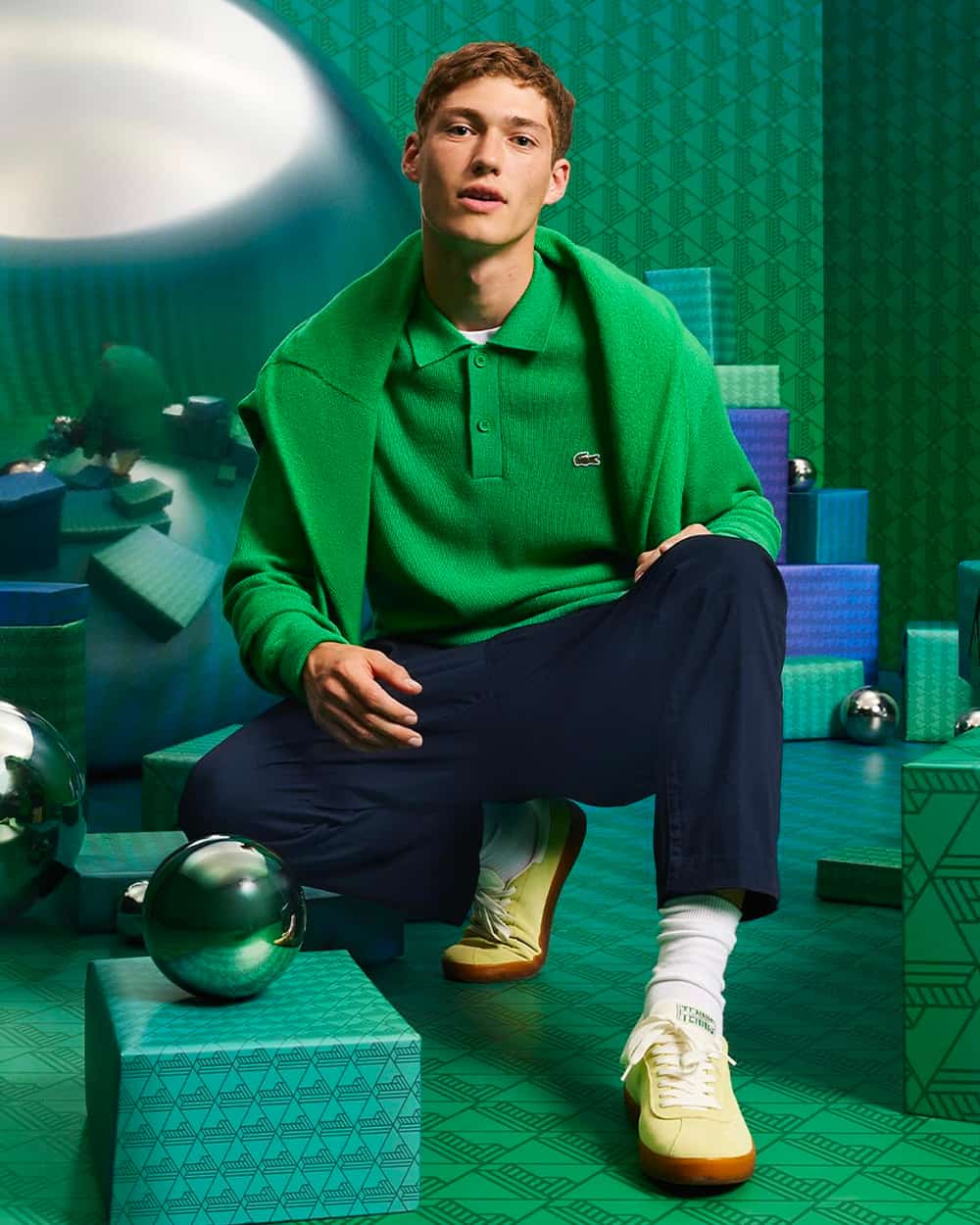 Man wearing Lacoste navy pants, white socks, green long-sleeve knitted polo shirt and green sweater with off-white gum sole sneakers