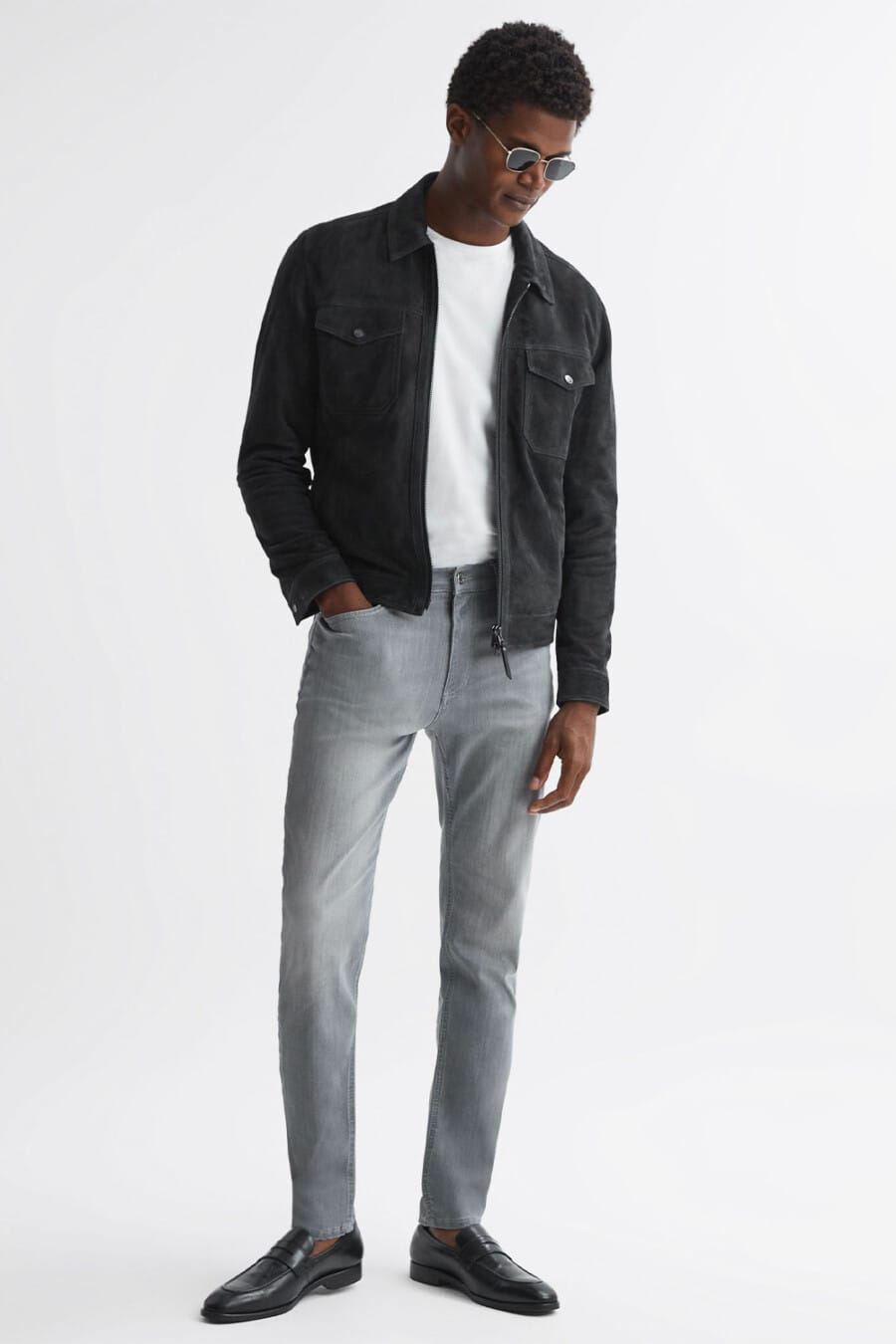 Men's grey jeans, white T-shirt, black suede blouson jacket and sockless black leather penny loafers outfit