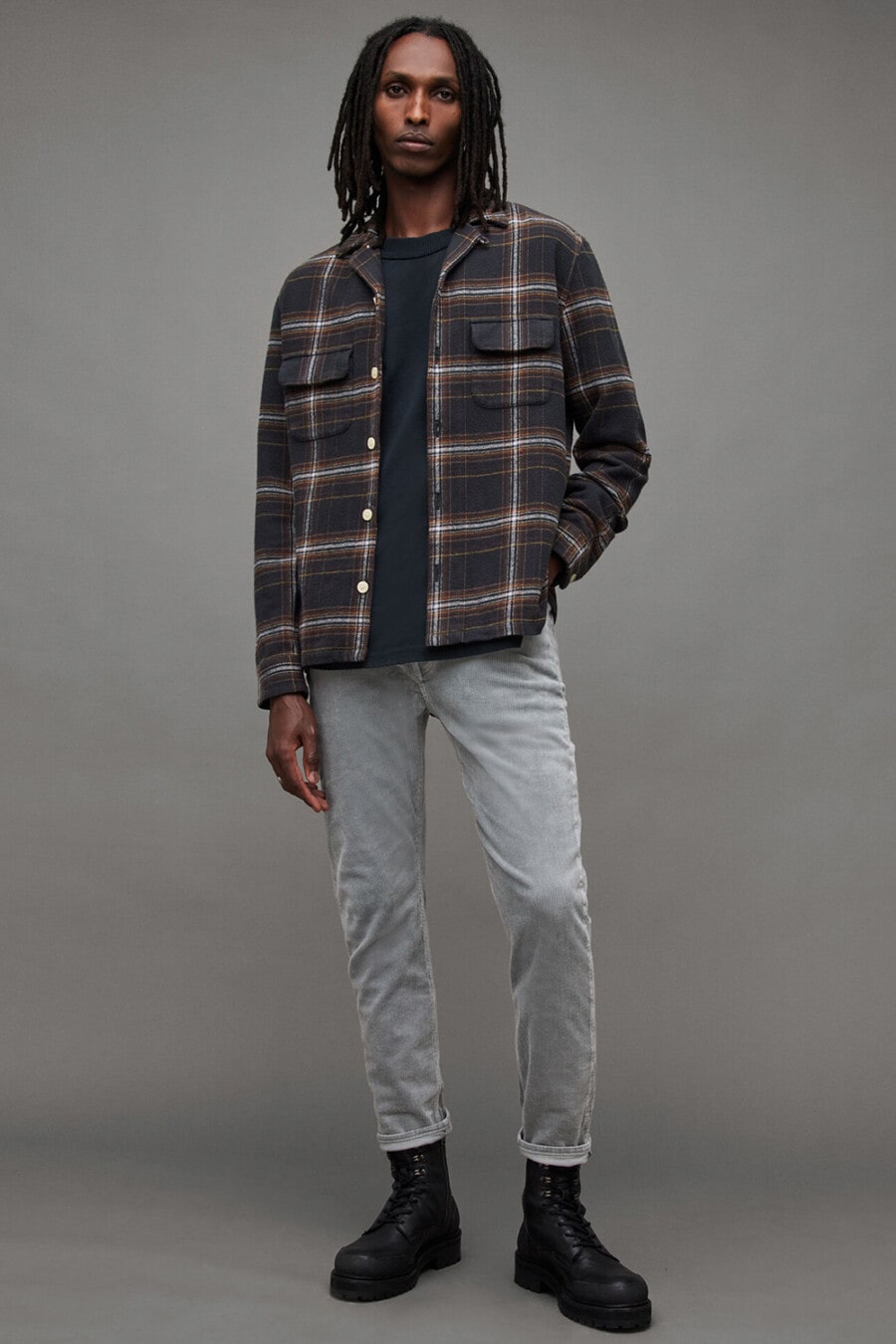 Men's grey jeans, black T-shirt, grey and red check flannel overshirt and black leather military boots outfit
