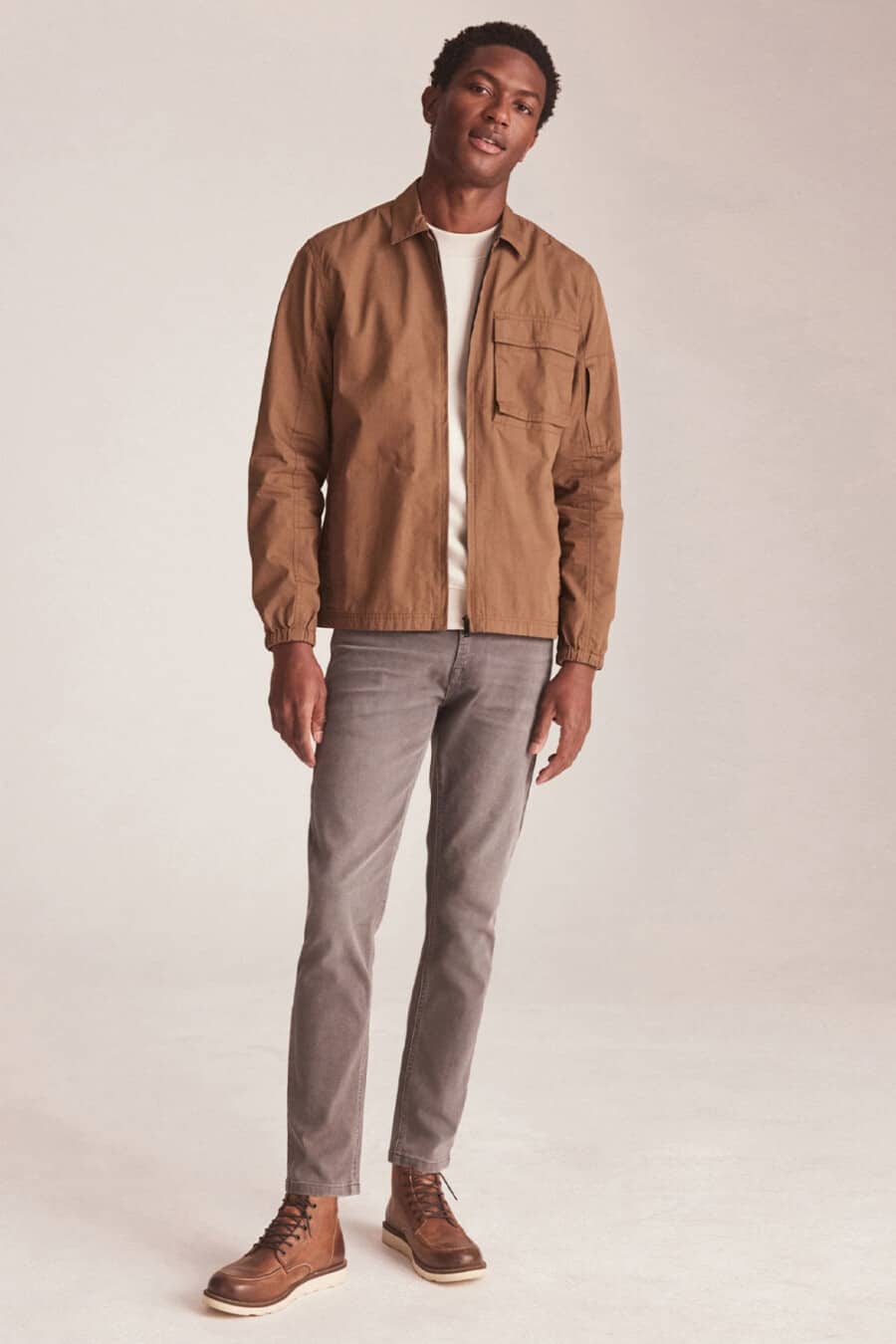 Men's grey jeans, white T-shirt, tan worker jacket and tan leather worker boots outfit