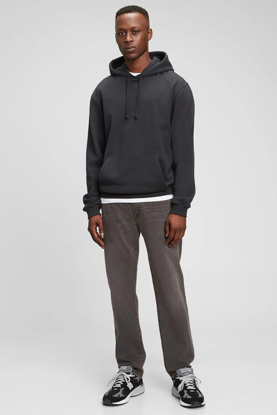 Men's loose dark grey jeans, white T-shirt, black hoodie and black running sneakers outfit