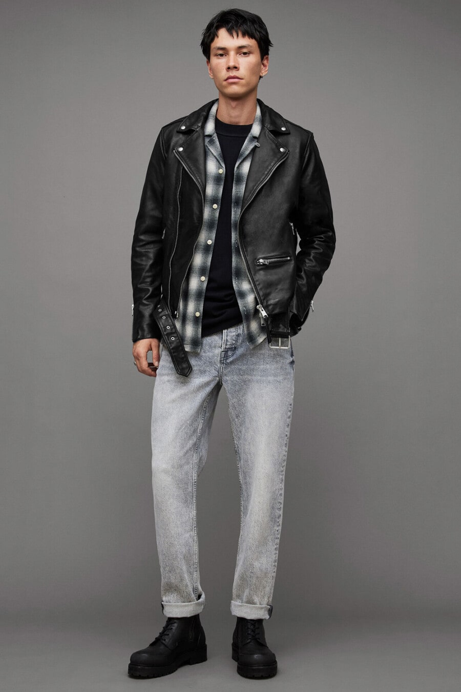 Men's washed grey jeans, black T-shirt, black/white flannel check shirt, black leather biker jacket and black leather boots outfit